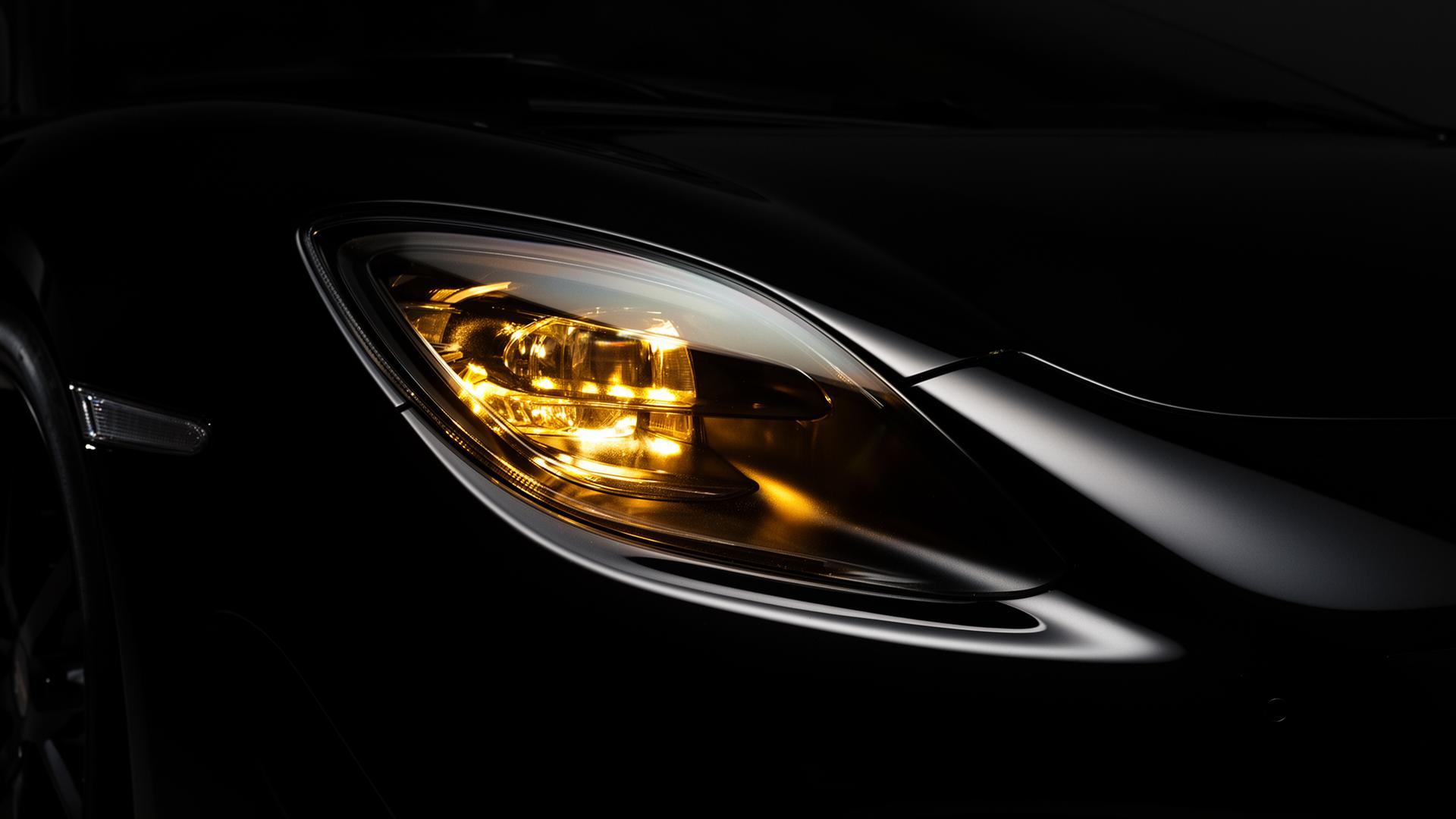 Phare d'une voiture de luxe reflétant une lumière dorée